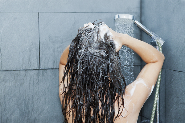 Femme en train de se laver les cheveux sous la douche (Istock)