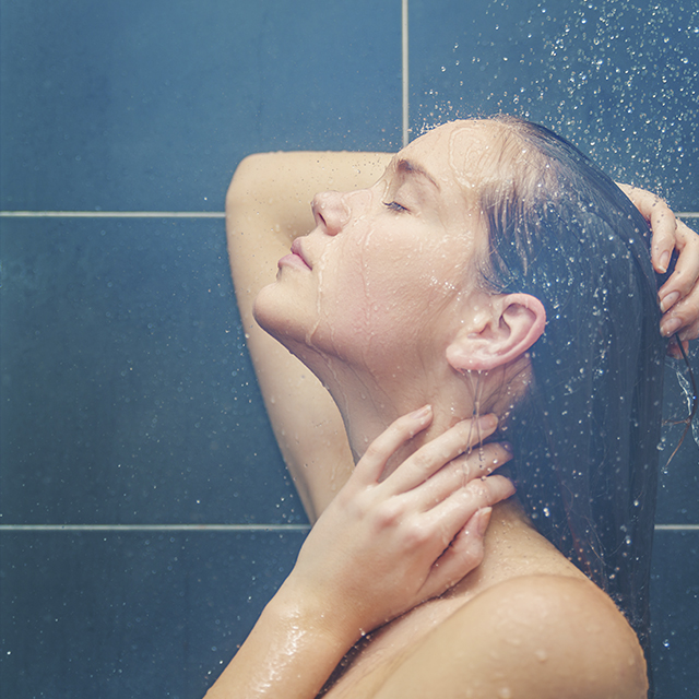 Femme nue sous la douche avec la main dans les cheveux (Istock)