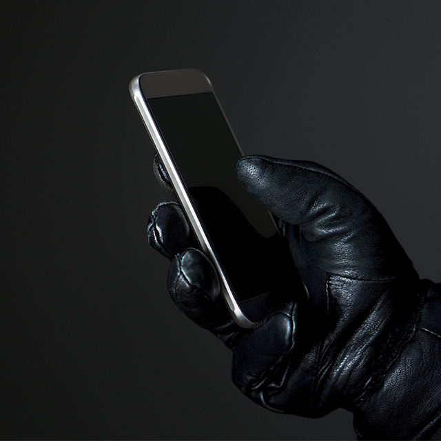 Main avec un gant en cuir tenant un téléphone (Istock)