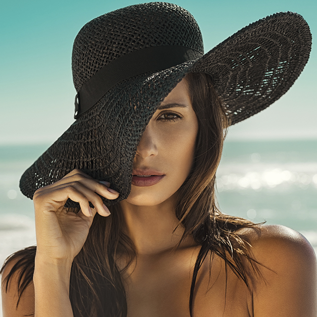 Jeune femme au bord de la plage en chapeau (Istock)